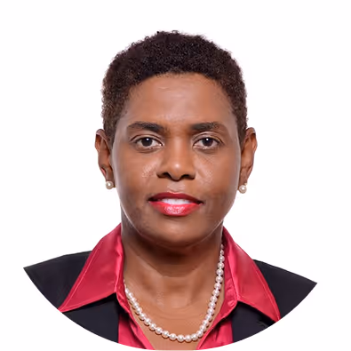Portrait of a woman with short curly hair wearing a dark blazer, red satin shirt, pearl necklace, and earrings against a white background.
