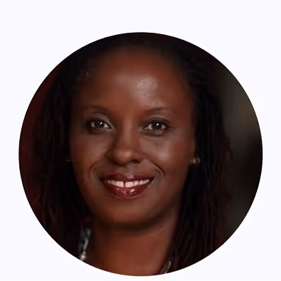 Portrait of a smiling woman with dark skin and long hair against a dark background.