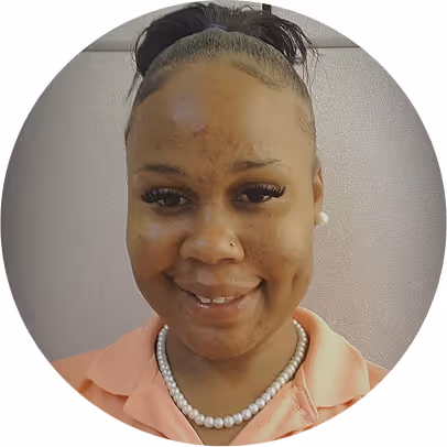 Smiling woman with hair pulled back, wearing a peach collared shirt and a pearl necklace.